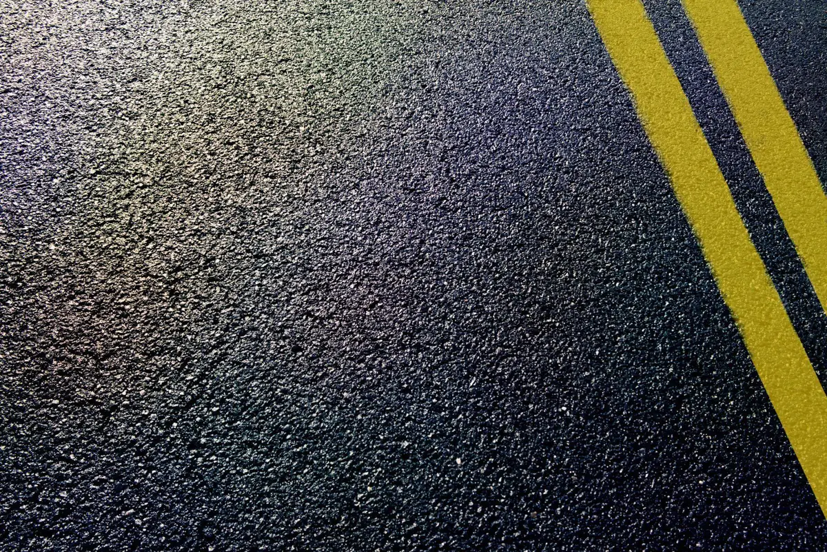 Close-up of freshly sealed dark asphalt with crisp yellow lines.